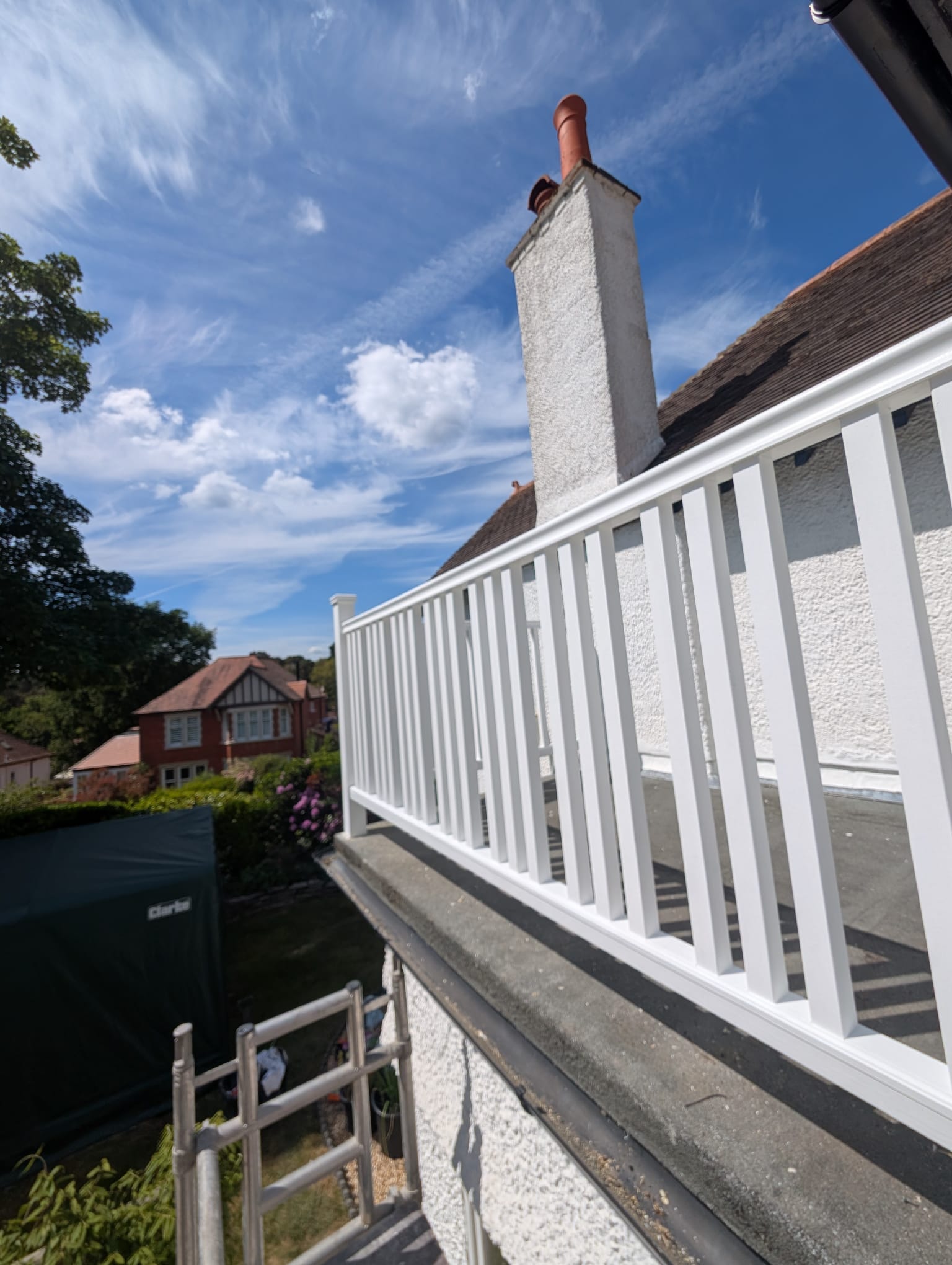 White painted balcony railings and rendered chimney against a blue sky