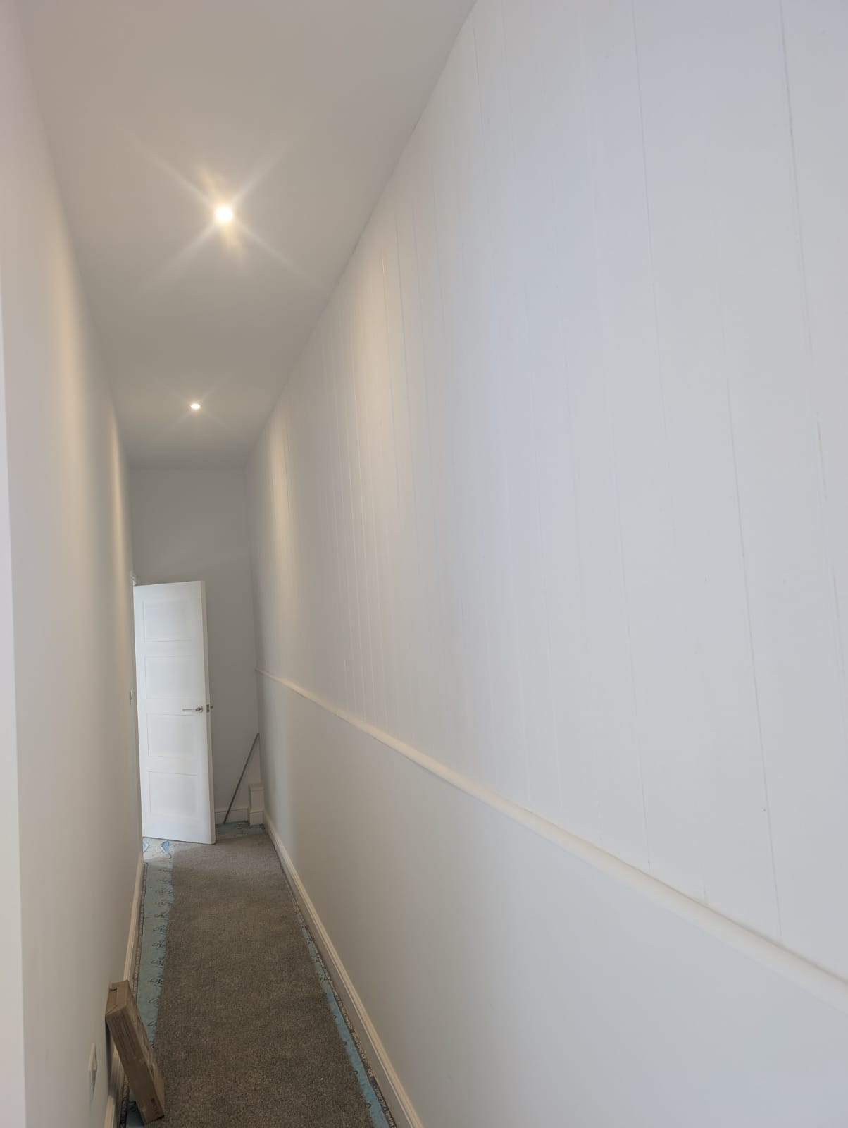 Pale painted hallway walls with vertical panelling and a dado rail